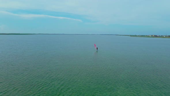 Drone Flight Over Calm Sea Surface with Glissing Windsurfer