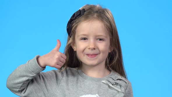 Little Girl Is Looking Happy, Smiling and Showing Thumbs Up