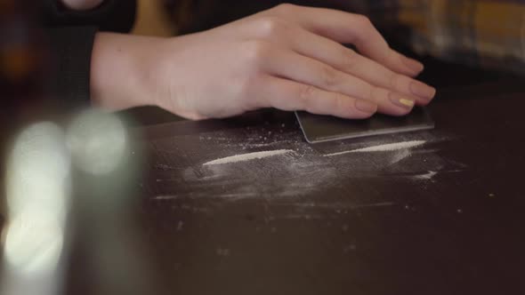 Close-up Addict Female Drug Making Cocaine Line with Black Credit Card on Wooden Surface at Home