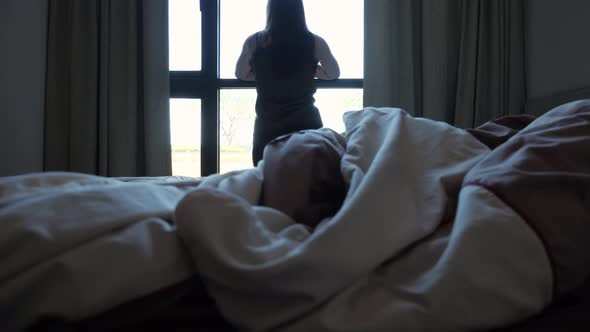 Brunette Woman Stretches Looking Out of Window in Hotel Room