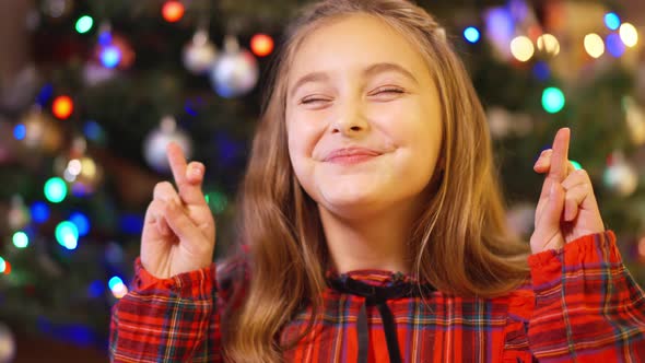 Headshot Portrait of Excited Charming Caucasian Girl Crossing Fingers Wishing Miracle on Christmas