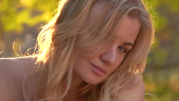 Blonde Woman Is Posing in Sunset Sunny Rays at the Autumn Park. Video Shooting Movement Camera with