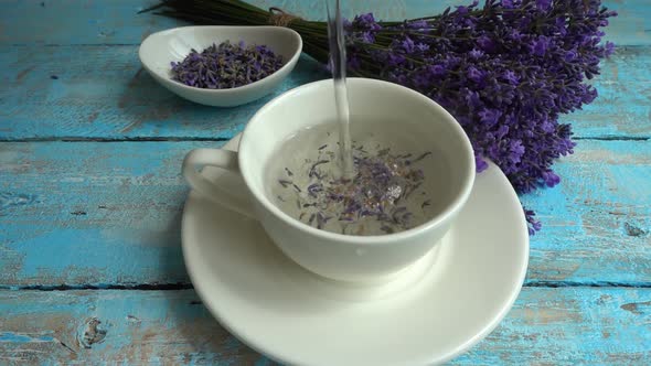 Tea from fresh lavender flowers on a vintage wooden background. Tea is brewed in hot water in a cup.