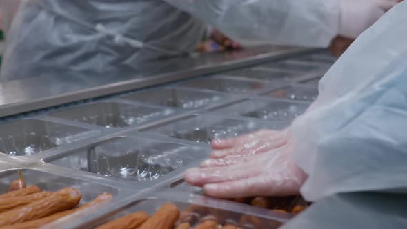 Close Up at the Workers of the Meat Processing Factory Placing Readymade Sausages in Plastic