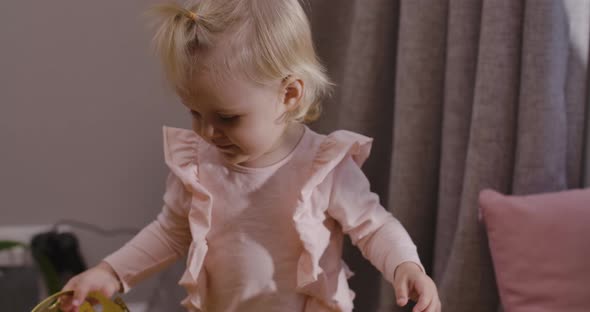 Close-up of Cute Blond Caucasian Child Playing with Toy Crown at Home