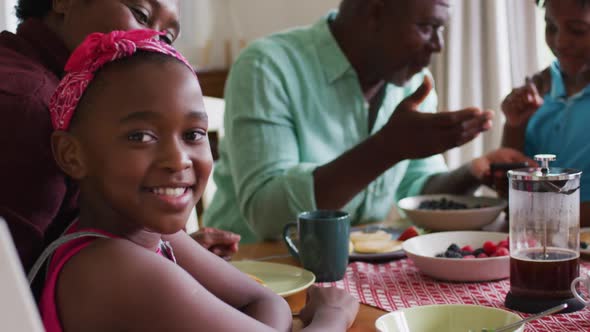 Portrait of african american girl smiling while having breakfast together with her family at home