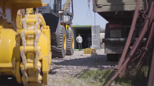 Caucasian Construction Workers Checking Equipment in Shipping Container at the Background As Heavy