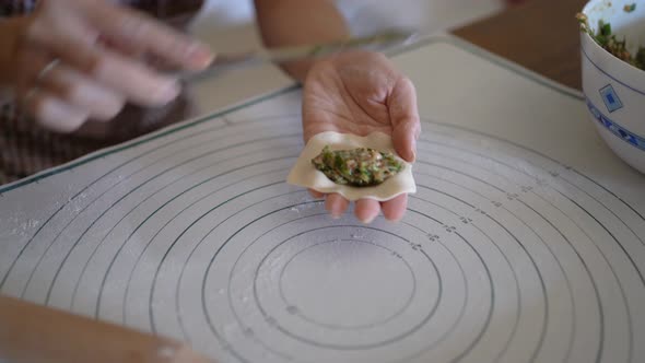 Female cook stuffing dough with meat