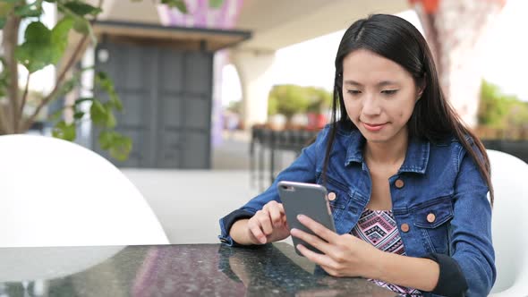 Woman using cellphone in outdoor coffee shop