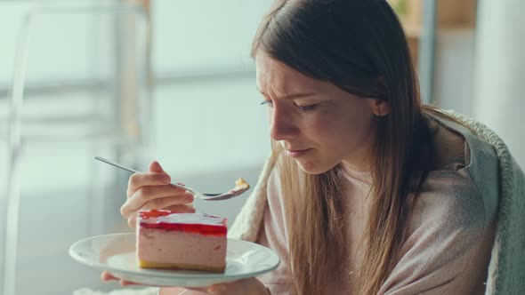 Heartbroken Young Woman Sitting on Sofa Crying Eating Cake