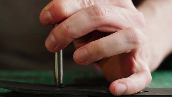 Man Tailor Cutting Artificial Leather Making Holes Closeup