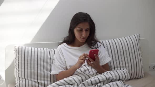 Woman Using Smartphone in Bed.