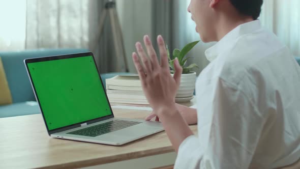 Asian Man Student Raises Hand And Asks A Question While Using Green Screen Computer At Home