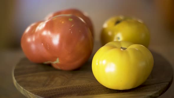 Red and yellow heirloom, fresh tomatoes turn slowly with shallow depth of field.