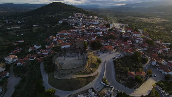 Drone flies then tilts over the Belmonte Castle and surrounding village with brick tiles.