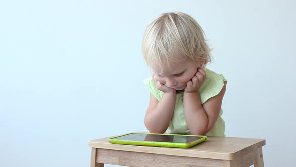 Little Girl Plays on the Tablet PC