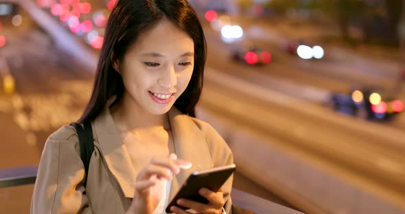 Woman Sending Message on Cellphone in City at Night