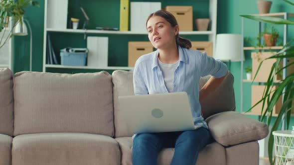 Freelancer Sitting on Sofa Working Remotely From Home Suddenly Feeling Pain