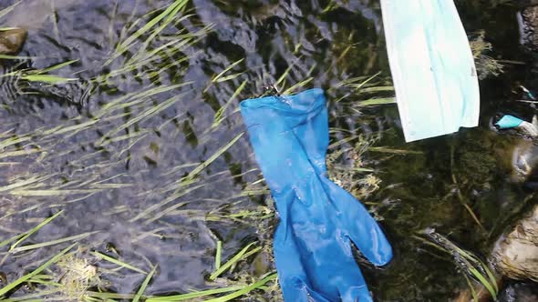 Blue Medical Mask with a Glove Float on the Surface of the Water