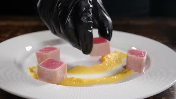 Professional Chef Decorates White Plate with Ready Tuna Fish Steak Cut Into Pieces