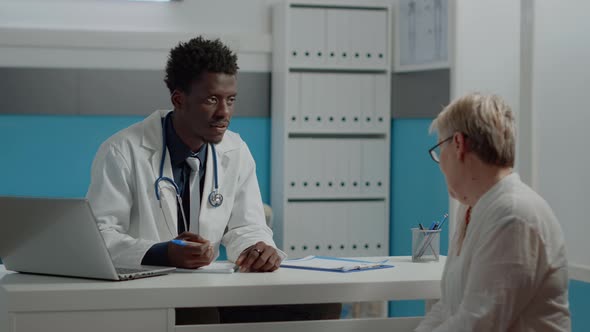 Black Man Working As Doctor Talking to Senior Woman