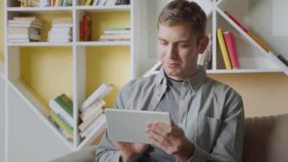 Smiling Man Using Tablet Relaxing on Sofa in Modern office.Concept of Young Business People Working