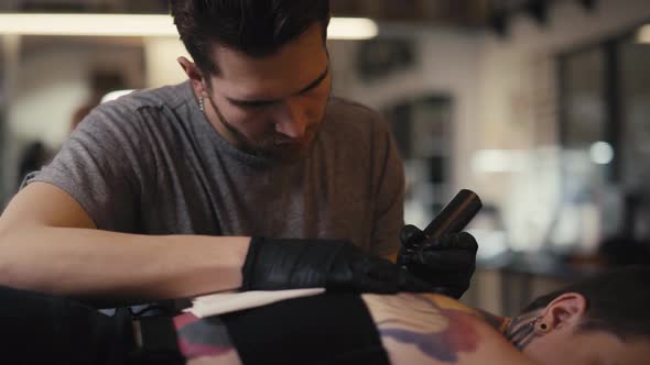 Caucasian man tattooing woman at the studio. Shot with RED helium camera in 8K.