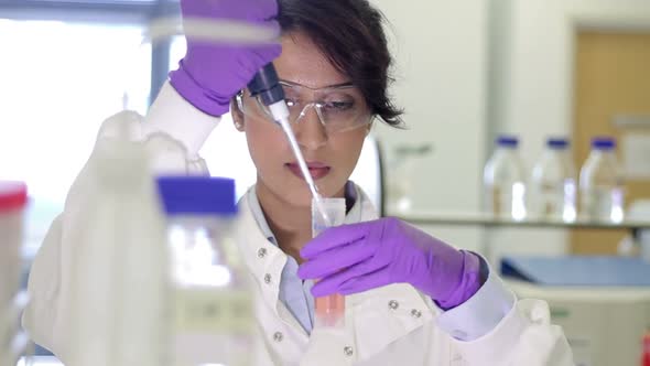 Scientist dropping liquid into vial in genetic laboratory