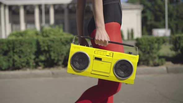 Unrecognizable Slim Woman in Red Legging Walking on Sunny Summer Street with Vintage Yellow Tape