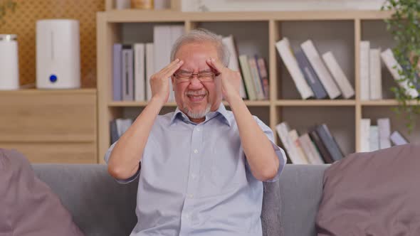 Asian elderly seniority man got headache and migraine. Old man got pain and illness on couch alone a