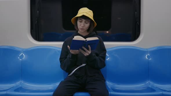 Young Caucasian Woman Reading Book at Metro Train