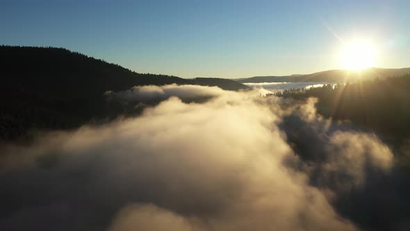 Aerial View of a Misty Lake. Dawn Dark Lights During Sunrise, Cold Weather. Flying Over Clouds