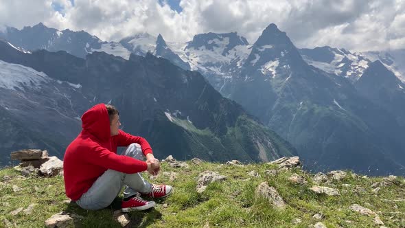 Adult Male in Red Hoodie with Hood Enjoying Beautiful View in Mountainous Area