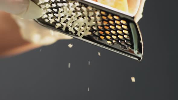 Person Grates Cheese Lump for Traditional Pasta on Black