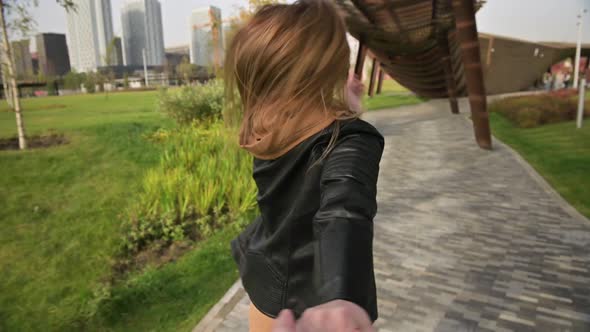 A young white woman actively invites for a walk, holding the viewer's hand. POV