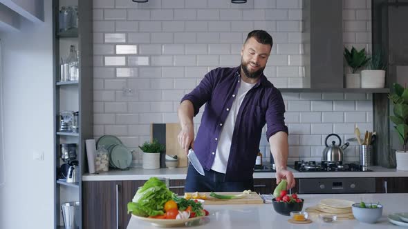 Young Man Slicing in the Air Vegetables in Slow Motion while Cooking at Home