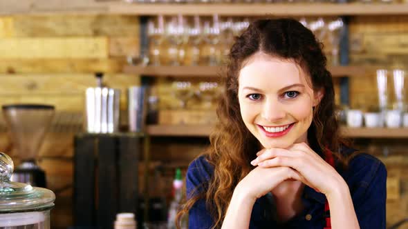 Portrait of smiling waitress leaning at counter