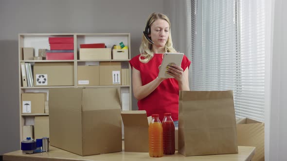 Warehouse Worker is Working in an Office Room Against Background of Boxes