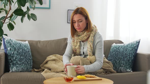 Sick Young Woman Drinking Tea with Lemon at Home