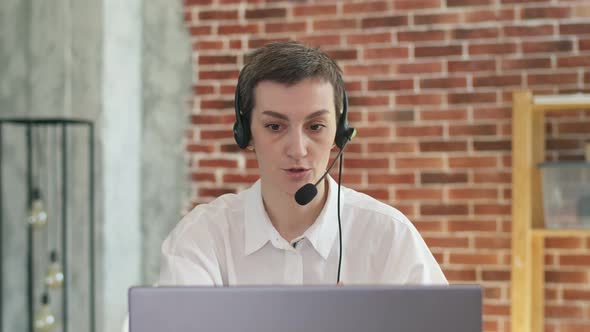 Call center operator is a woman in a headset talking via video link to laptop