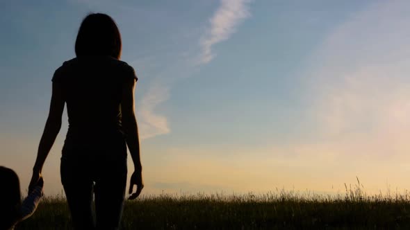 Family Silhouette at Sunset. Mom, Son and Daughter Enjoy a Beautiful Sunset on a Summer Evening