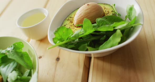 Video of bowls of fresh salad with green leaves on wooden background