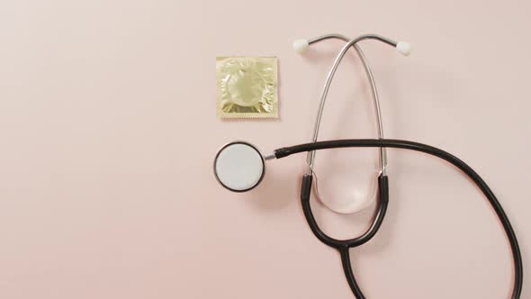 Video of close up of stethoscope with condom on pink background