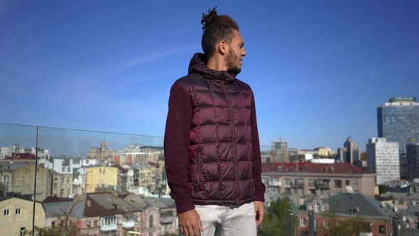 Handsome Young African American Man Standing on Rooftop at Background of Urban City Looking Around