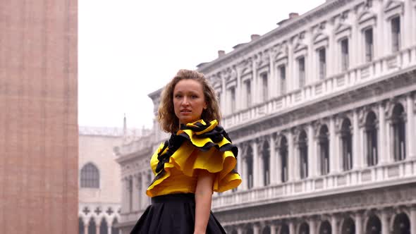 Woman in Designer Carnival Dress Poses Against Empty Square