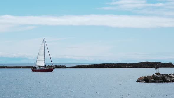 Sailboat on peaceful water in harbor against brilliant blue sky