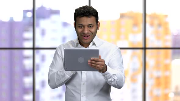 Young Darkskinned Man in Formal Shirt Holding Tablet Pc with Both Hands