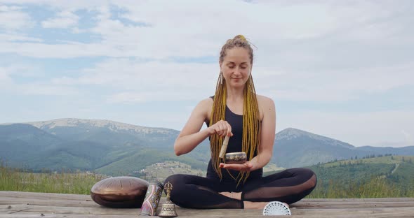 Woman Playing on Tibetan Singing Bowl in Lotus Pose