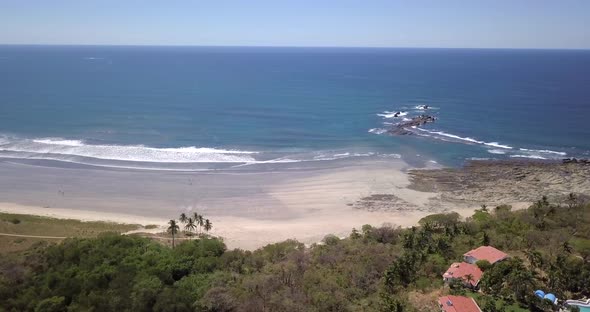 Aerial drone view of the beach, rocks and tide pools in Guiones, Nosara, Costa Rica.