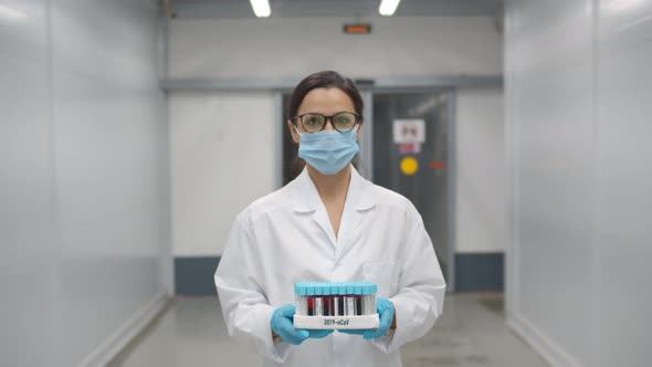 Woman Doctor in Safety Mask and Gloves Carrying Tray with Blood Samples for Covid-19 Test